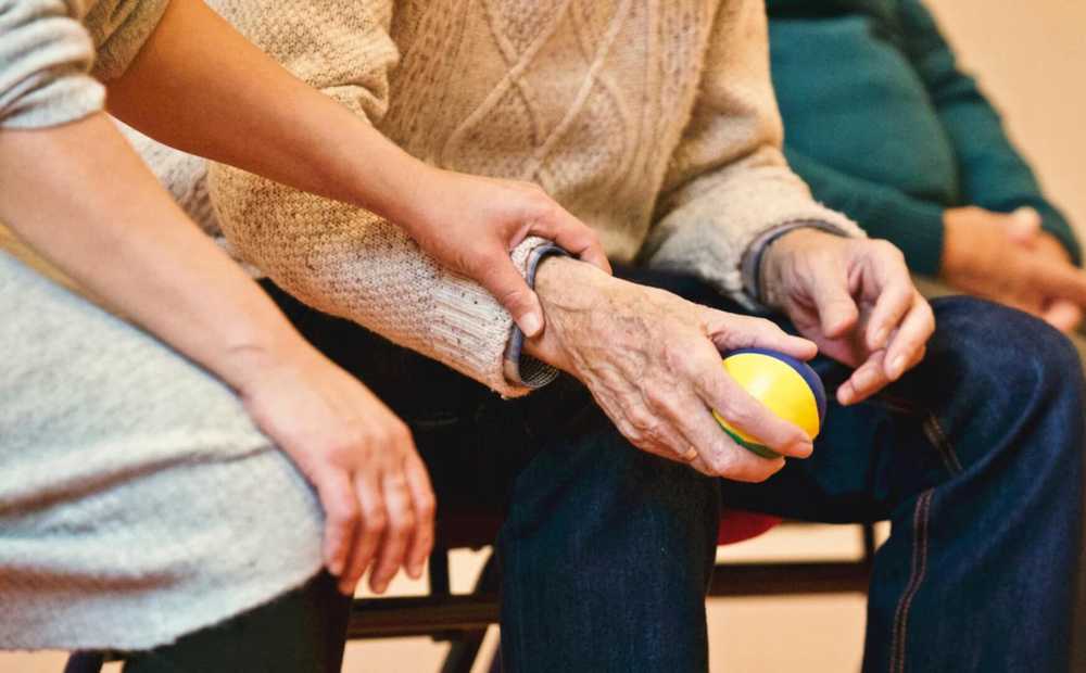 holding an elderly person's hand, who is also holding a ball